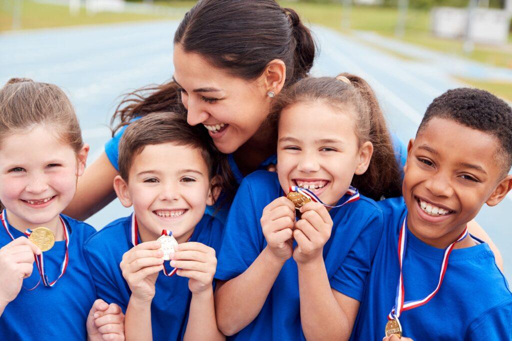 vier Kinder im Trikot und Medaille in der Hand