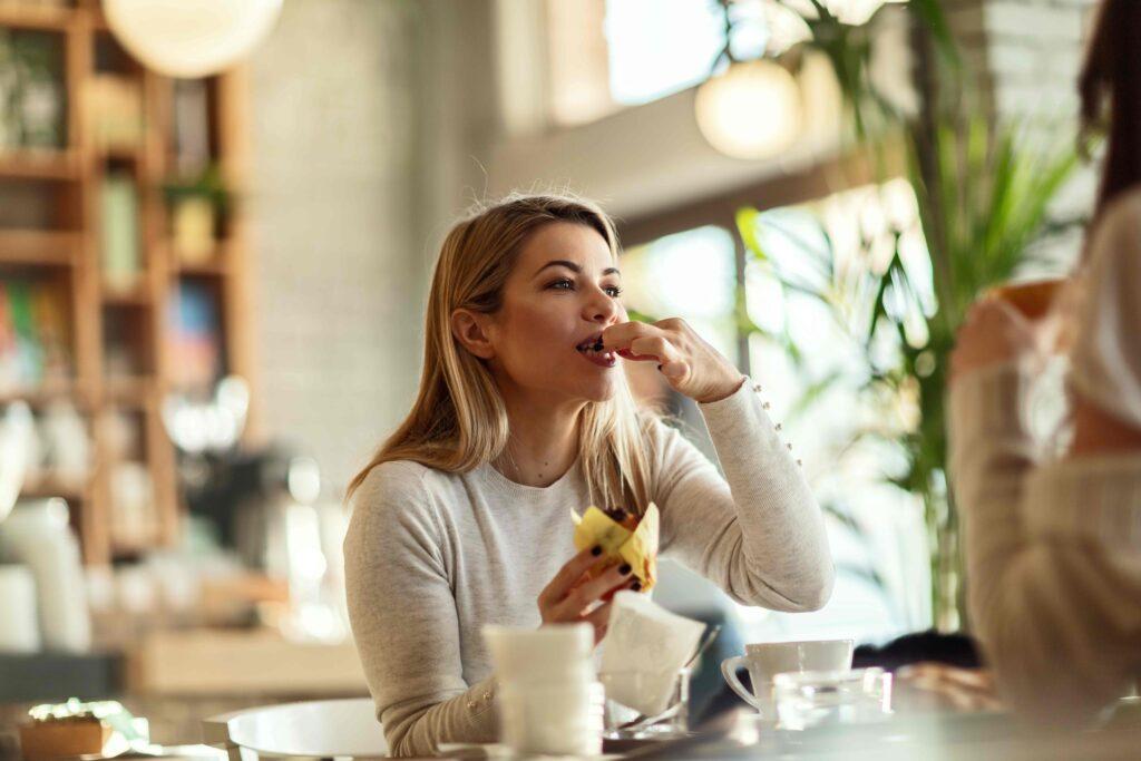 Junge schöne Frau isst Muffin in einem Café.