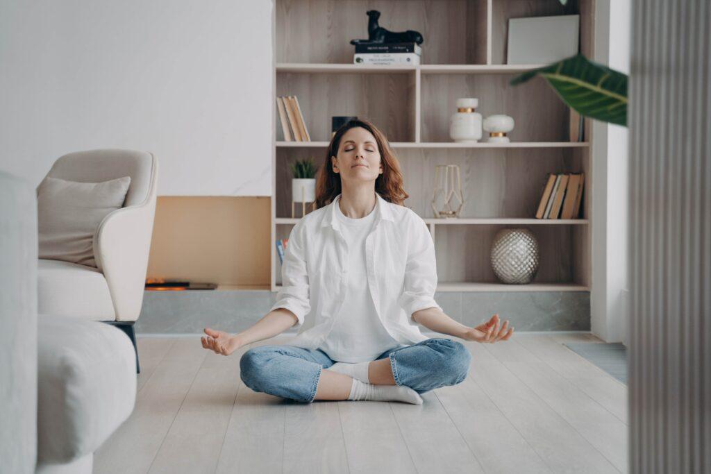 Frau meditiert, praktiziert Yoga und atmet zu Hause frische Luft auf dem Boden.