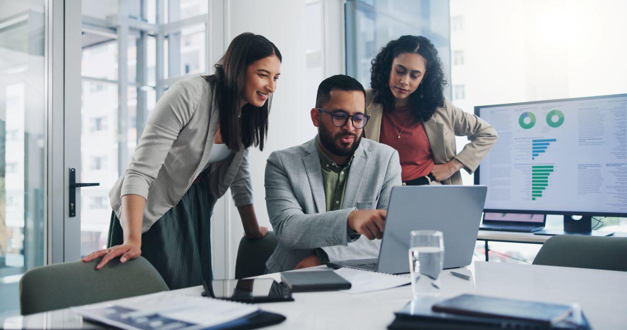 Ein Team arbeitet an einem Laptop, mit Datenanalyse-Dashboards im Hintergrund, das smarte Unternehmenslösungen wie Sage 100 unterstützt.