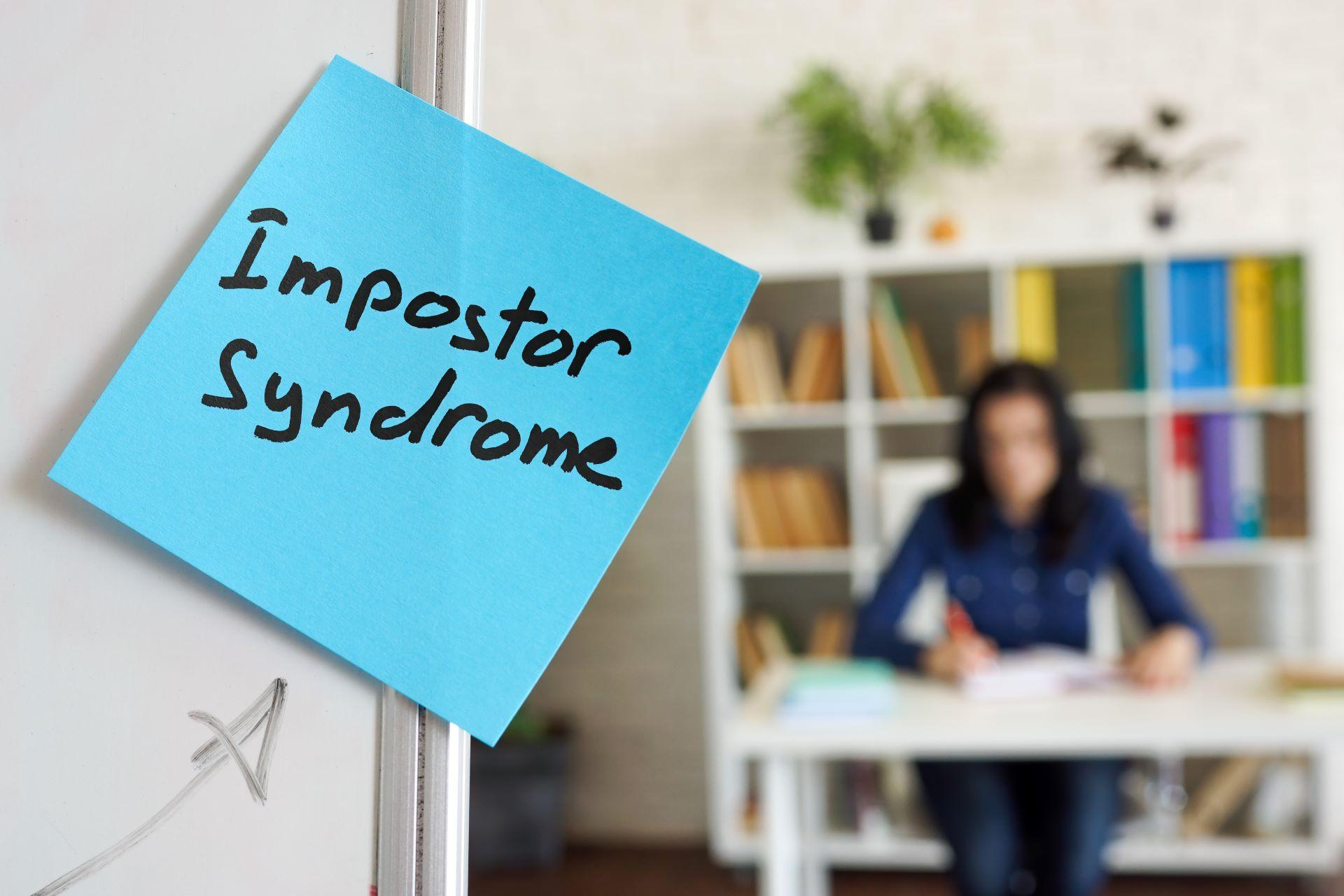 Blauer Post-it mit Aufschrift Impostor Syndrome im Büro